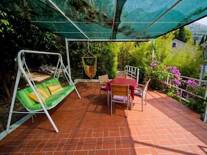 A patio with a swing, a table with chairs, and a hanging chair. - Apartments Villa Mare - One Bedroom Apartment With Balcony and Sea View (Zupa dubrovacka)
