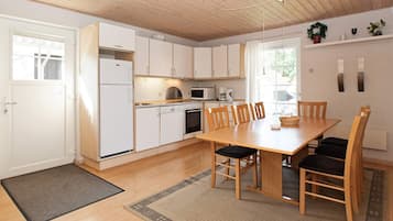 Eine kleine Küche mit weißen Schränken, einem Holztisch und einem schwarzen Teppich.
