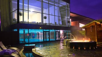 Ein modernes Gebäude mit Glasfassade, einem Schwimmbecken und einem Whirlpool-Bereich.