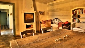 A dining area with a wooden table, chairs, and a fireplace. - Holiday Home Casa Nanda (Mombaruzzo)