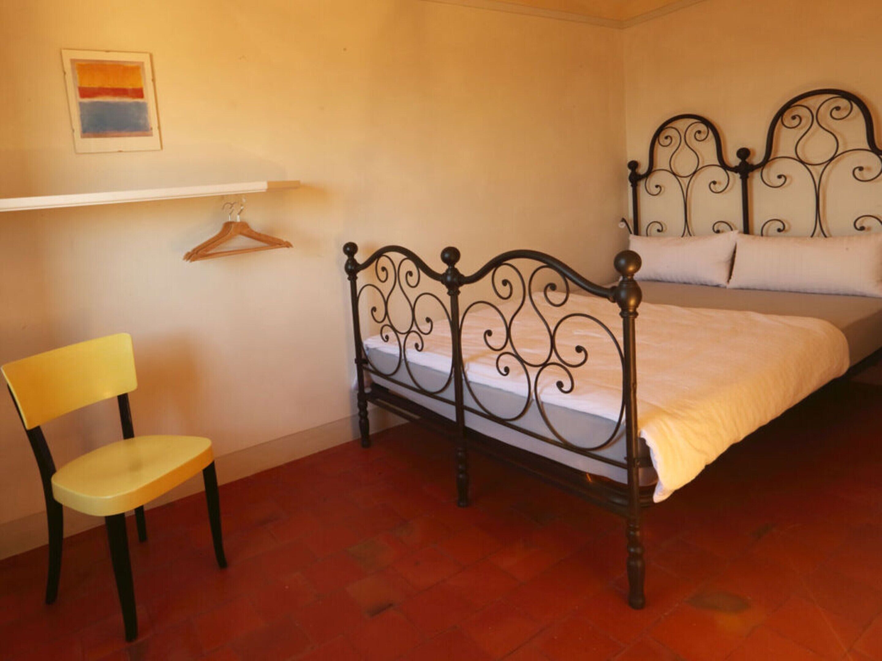 Ein Schlafzimmer mit einem Bett, einem Sessel und einem an der Wand befestigten Regal.