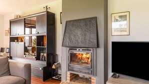 A modern living room with a fireplace, built-in shelving, a flat-screen TV, and a comfortable seating area. - Holiday Home Les Hirondelle for 8 Persons (Bievre)
