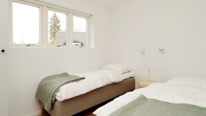 A bedroom with a single bed, a bedside table, a window, and a view of a tree and building outside. - 5 Star Holiday Home in Nysted (Nysted)