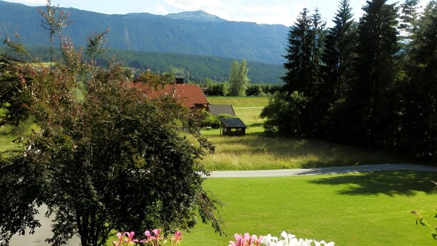A rural landscape with a house, a grassy field, and mountains in the background. - Apartment With Sauna and Lakeview (Hermagor-Pressegger See)