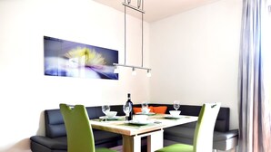 A modern dining area with a rectangular table, green chairs, and a black sofa. - Apartment With Sauna and Lakeview (Hermagor-Pressegger See)