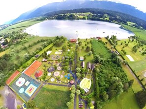 Vue aérienne d’un parc avec un lac, des aires de jeux et des installations sportives.