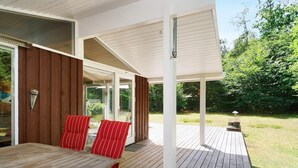 A wooden deck with a table and chairs, a covered patio area, and a view of the surrounding greenery. - 5 Person Holiday Home in Frederiksvaerk (Frederiksvaerk)
