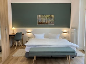 A modern bedroom with a bed, bedside tables, a desk, and a chair.