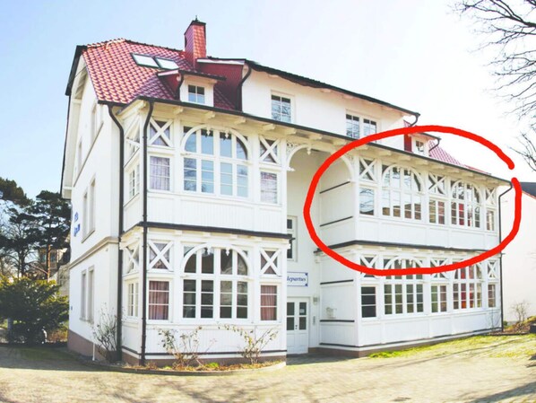A two-story building with a white facade and red-tiled roof.