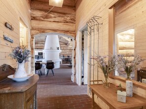 Un intérieur en bois avec un sol en briques, un espace cuisine aux couleurs claires et une table à manger avec des chaises.
