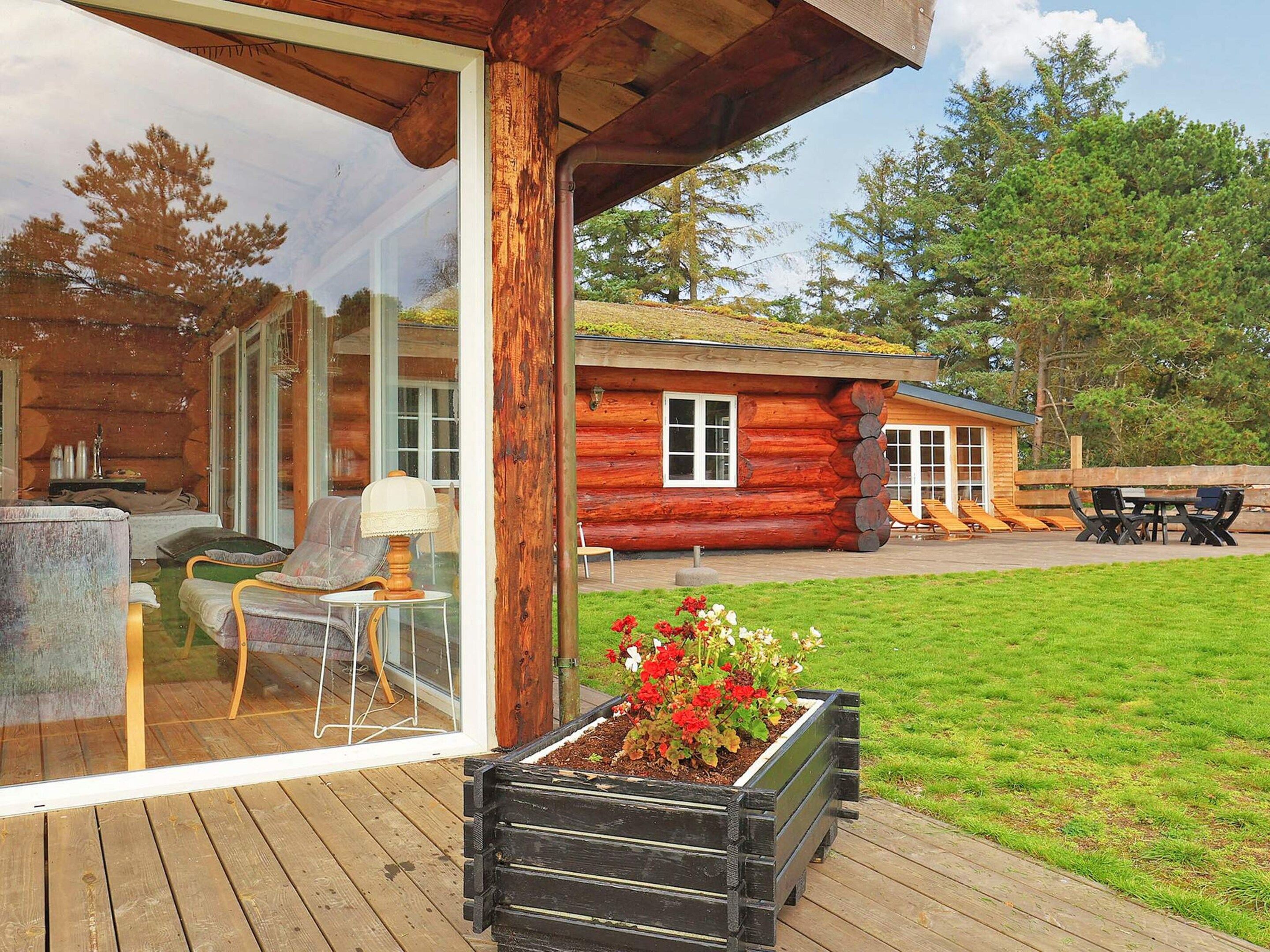 Une cabane en rondins dotée d’une terrasse, d’un espace salon extérieur et d’un jardinière.