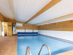 Une piscine intérieure avec des murs en bois et un sol carrelé.