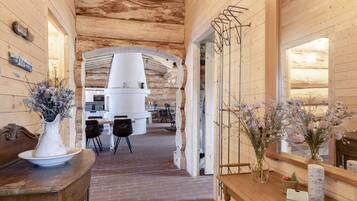 Un interior de madera con piso de ladrillo, una cocina blanca y una mesa de comedor con sillas.