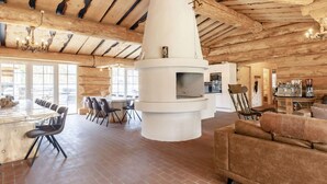 A spacious interior with a large fireplace, wooden beams, a dining area, and a kitchen. - 24 Person Holiday Home in Laeso-by Traum (Læsø)