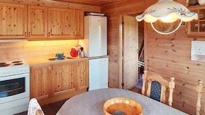 A wooden cabin interior with a kitchen area, including a stove, refrigerator, and wooden cabinets. - 8 Person Holiday Home in Tjorhom (Sirdal)