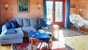A cozy cabin-style room with a sofa, a small table with a vase, a chair, and a lamp. - 8 Person Holiday Home in Tjorhom (Sirdal)