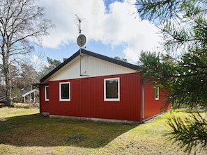 A red building with a satellite dish, two windows, and a small porch. - 6 Person Holiday Home in Aakirkeby (Akirkeby)