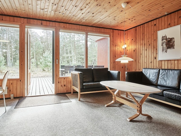 A wooden interior with a sofa, a table, and a bench.