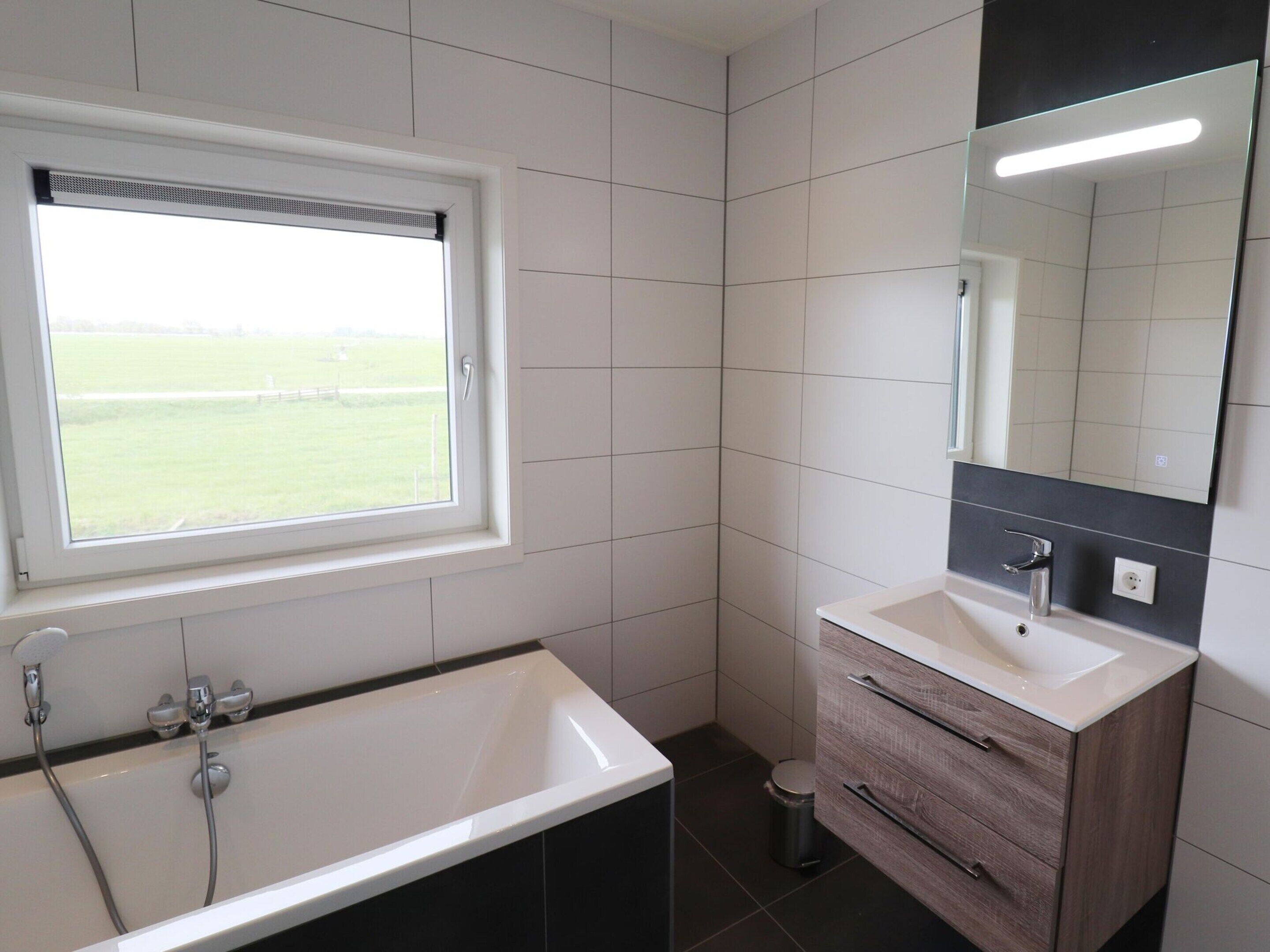 A modern bathroom with a large bathtub, a sink, and a mirror.