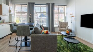 A modern living room with a sofa, chairs, a dining table, and a TV. - 2 Adjacent Apartments in the Heart of Sneek (Sneek)