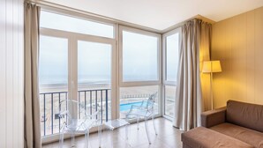 A room with a balcony, clear chairs, a sofa, and a lamp. - Apartment by Belgian Coast With Beach Views (Koksijde)