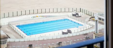 Una amplia piscina cubierta con un paseo perimetral y una zona de playa arenosa.
