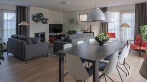 Un soggiorno moderno con un divano grigio, un tavolo da pranzo con sedie, una TV a schermo piatto e un camino.