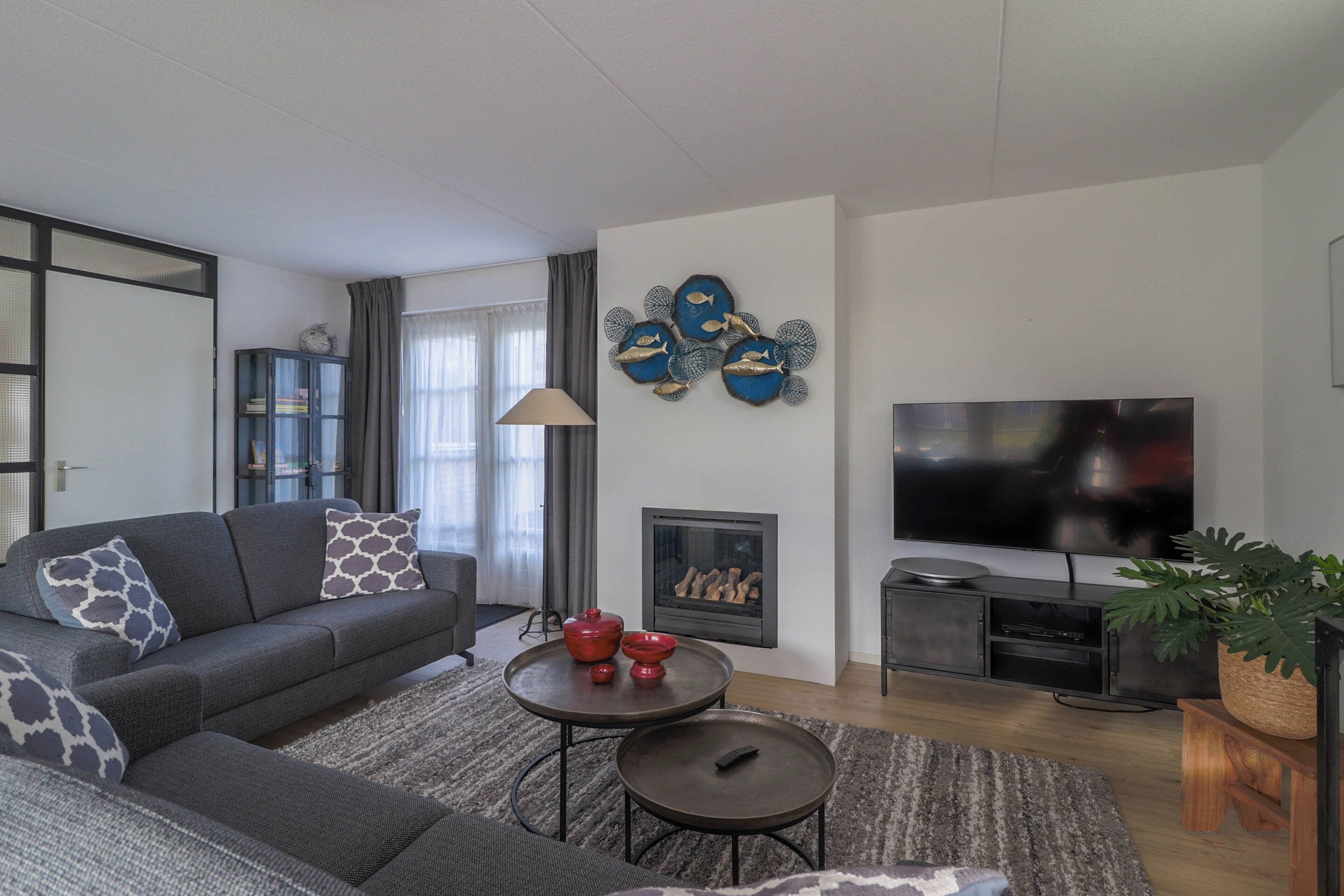 Una sala de estar moderna con un sofá, una chimenea, un televisor y decoración en la pared.