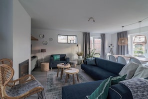Una sala moderna con un sofá, dos mesas auxiliares, una mesa de centro y una silla de mimbre.