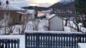 A snowy landscape with a house, a wooden fence, and a mountain in the background. - 4 Star Holiday Home in Vikholmen (Nesna)