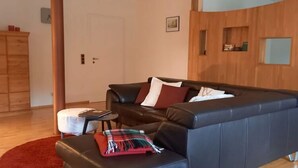 Una sala de estar moderna con un sofá de cuero negro, una alfombra roja y un mueble de madera.