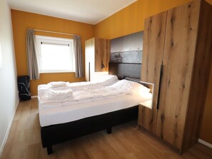 A bedroom with a bed, wooden wardrobe, and a window with curtains. - Villa in Leons With Sloop Rentals (Leons)