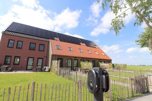 A building with a brick facade, solar panels on the roof, and a fenced outdoor area with tables and chairs. - Villa in Leons With Sloop Rentals (Leons)