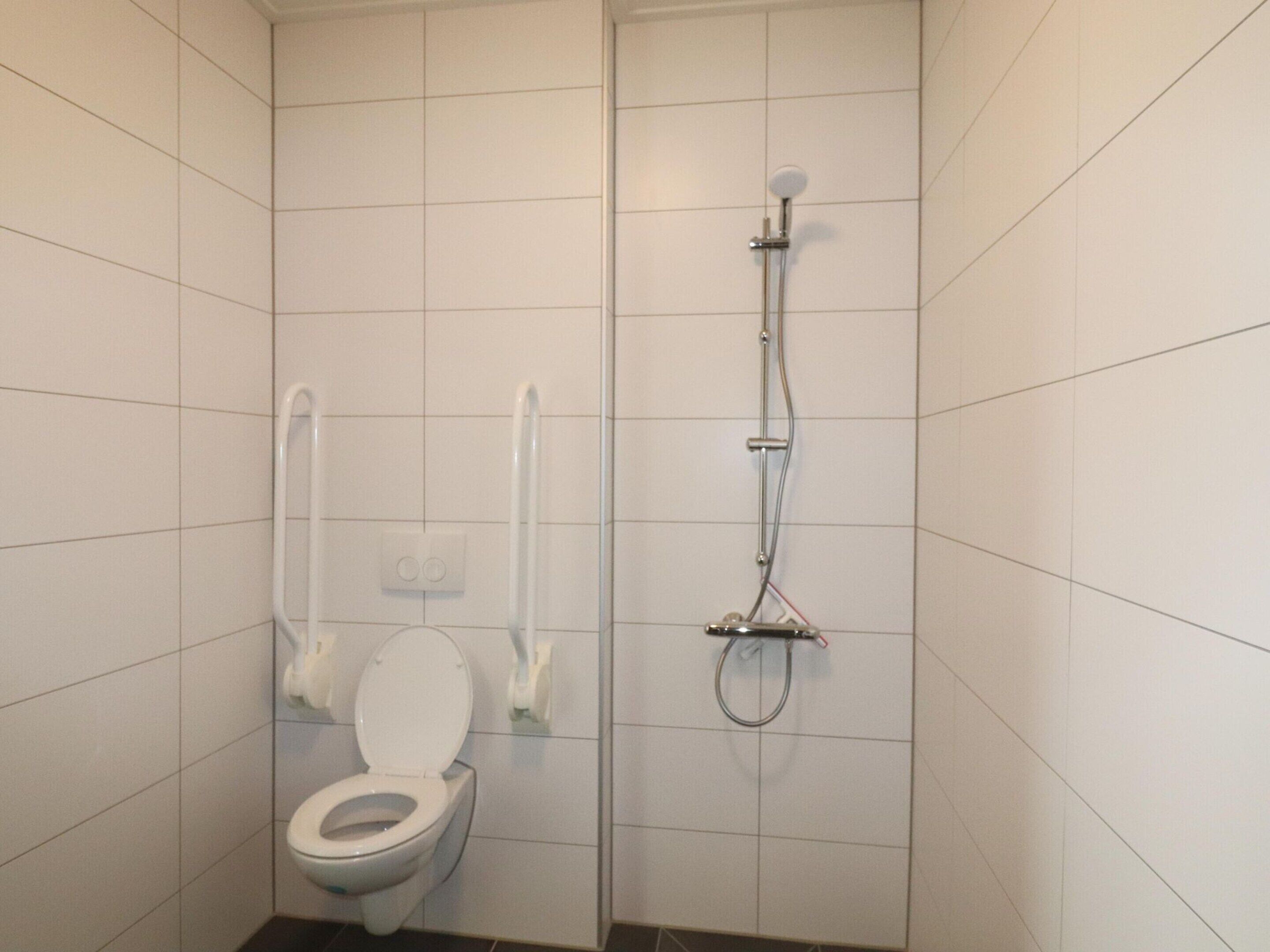 A small, tiled bathroom with a toilet and a shower.
