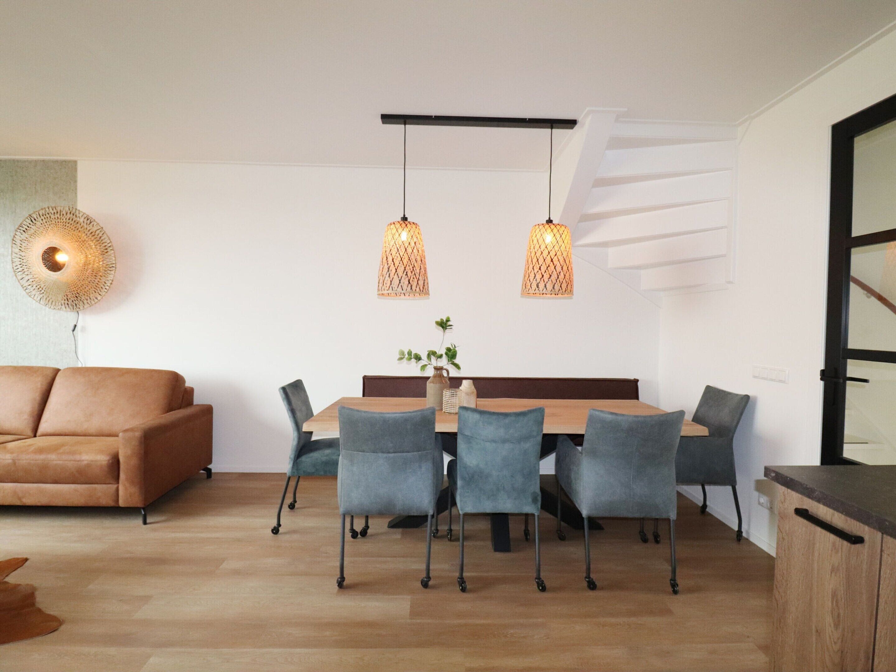 Ein stilvoller Essbereich mit einem Holztisch, sechs Stühlen und zwei hängenden Pendelleuchten.