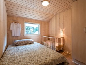 A room with a bed, a crib, a window, and a wall-mounted light. - 6 Person Holiday Home in Norre Nebel (Norre Nebel)