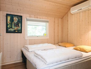 A bedroom with a bed, a window, and a painting on the wall. - 6 Person Holiday Home in Norre Nebel (Norre Nebel)