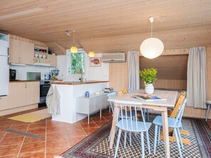 A modern kitchen with wooden cabinets, a dining area with a table and chairs, and a large window. - 6 Person Holiday Home in Norre Nebel (Norre Nebel)