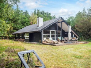 A modern house with a large deck, outdoor seating, and a view of the surrounding forest. - 6 Person Holiday Home in Norre Nebel (Norre Nebel)