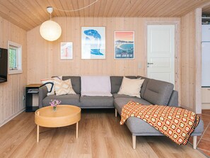 A cozy living room with a grey sofa, a round wooden coffee table, and a colorful blanket. - 6 Person Holiday Home in Norre Nebel (Norre Nebel)