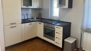 A modern kitchen with white cabinets, a black countertop, a window, and a radiator. - Medulin Burle A4+1 (Medulin)