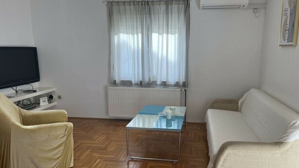 A living room with a television, a sofa, a chair, a coffee table, and a window with curtains. - Medulin Burle A4+1 (Medulin)