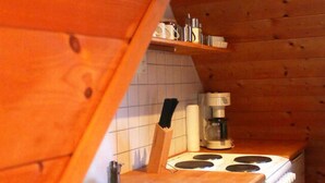 Eine kleine Küche mit Holzwänden, einer eingebauten Spüle, einem Herd und einem Geschirrspüler.