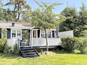 A house with a porch, a staircase leading to a deck, and a small garden area. - 4 Star Holiday Home in Aplared (Aplared)