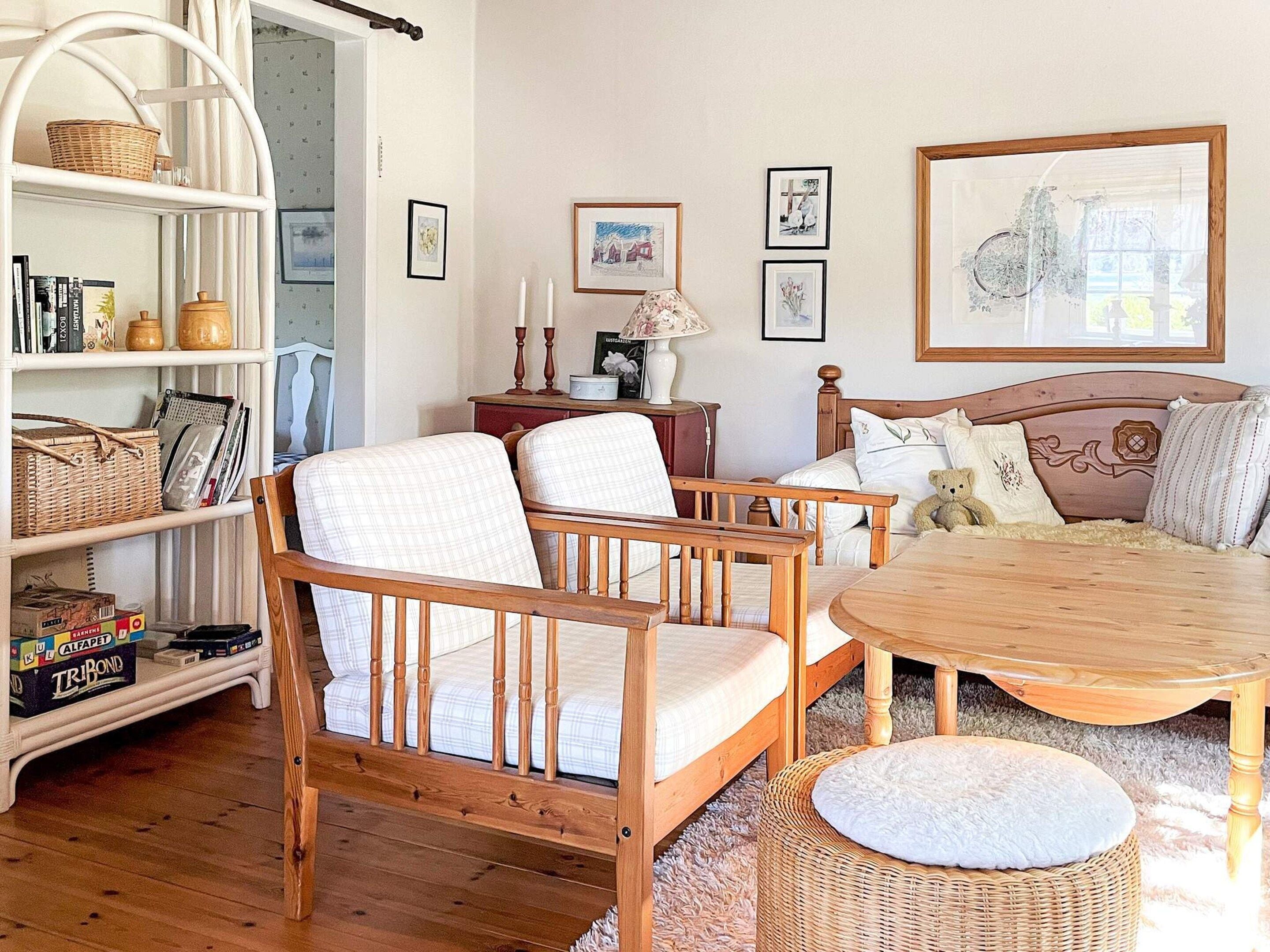 A cozy room with a wooden bed, a round table, a wicker chair, and a bookshelf.