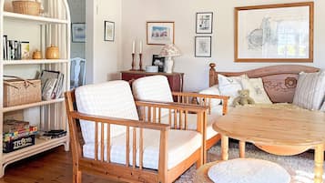 A cozy room with a wooden bed, a round table, a wicker chair, and a bookshelf.