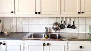 A kitchen with white cabinets, a stainless steel sink, and hanging kitchen utensils. - 4 Star Holiday Home in Aplared (Aplared)