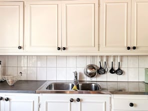A kitchen with white cabinets, a stainless steel sink, and hanging kitchen utensils. - 4 Star Holiday Home in Aplared (Aplared)