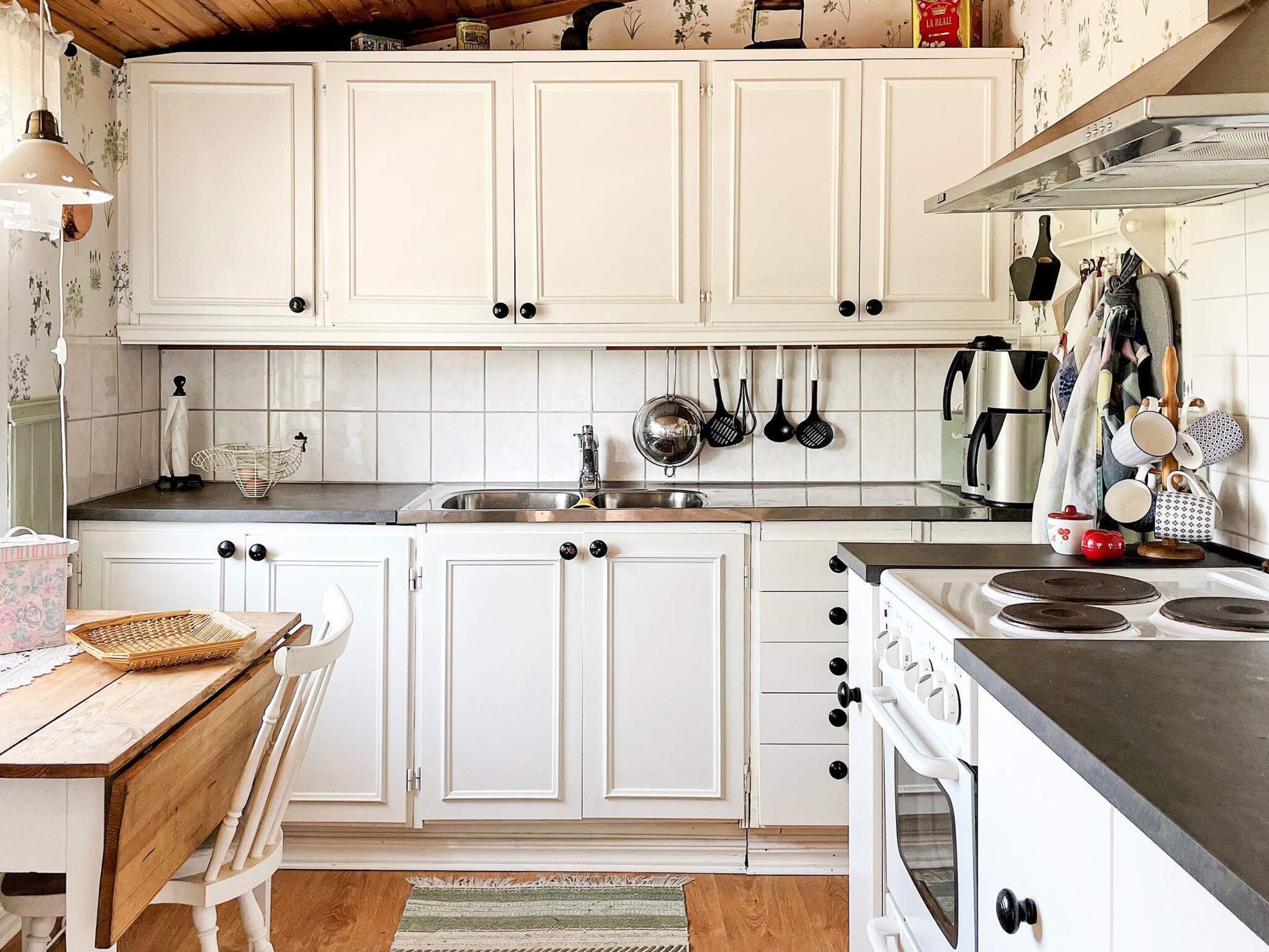 A kitchen with white cabinets, a stove, and various kitchen utensils.