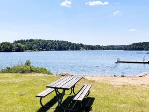A picnic table on a grassy area by a lake with a dock and boats in the background. - 4 Star Holiday Home in Aplared (Aplared)